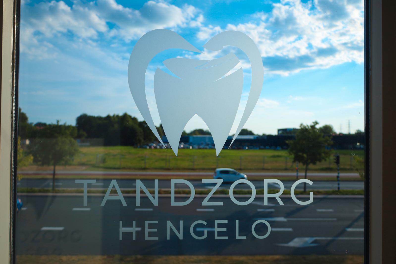 Het logo van Tandzorg Hengelo op het raam van de praktijk